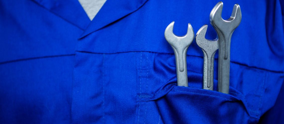 Mid section of mechanic with spanners in pockets at repair garage