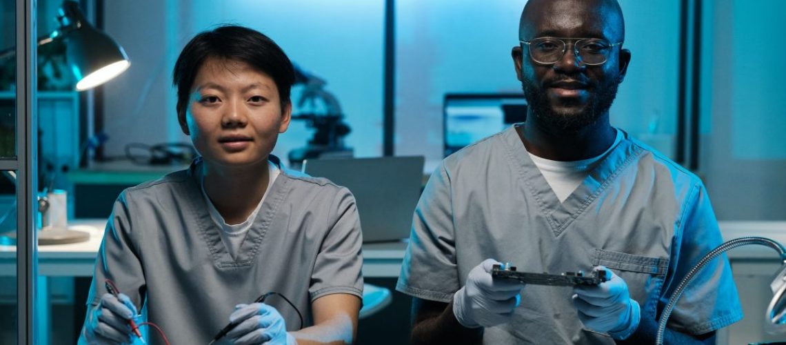 two-young-successful-technicians-in-gloves-and-uniform-working-by-desk-1.jpg